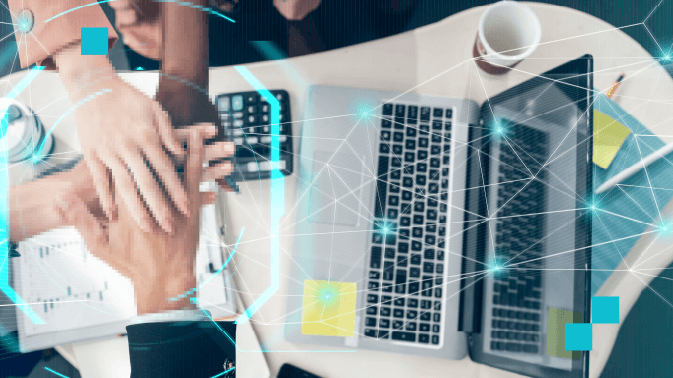 Vista cenital de un equipo de trabajo colaborando en una oficina moderna. Varias manos se unen en el centro de la mesa —símbolo de cooperación— mientras alrededor hay laptops, documentos con gráficos, una calculadora y una taza de café. Sobre la escena flota una red digital de líneas y puntos luminosos en azul cian, conectando los elementos y representando la interconexión tecnológica. La imagen simboliza el trabajo en equipo, la sinergia entre personas y tecnología, y la toma de decisiones basada en datos.